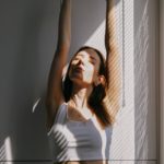 woman in white tank top standing beside white wall