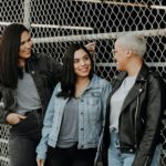 3 women standing beside gray metal fence
