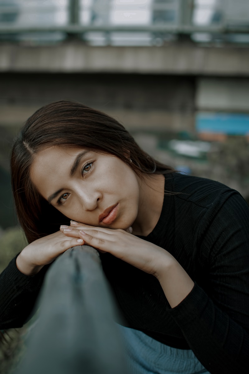 a woman leaning on a rail with her hand on her chin